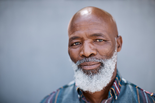 Portrait of a mature man standing against a grey background