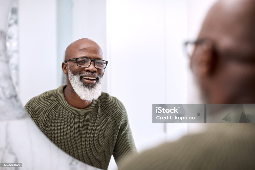 Many say that I look quite good for my age Shot of a mature man looking at his face in the bathroom at home Mirror - Object Stock Photo