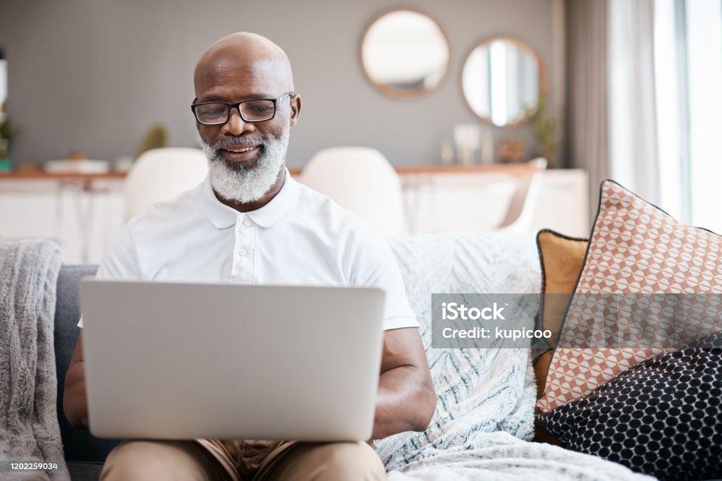 Technology hosts entertainment for all ages Shot of a mature man using a laptop at home Laptop Stock Photo