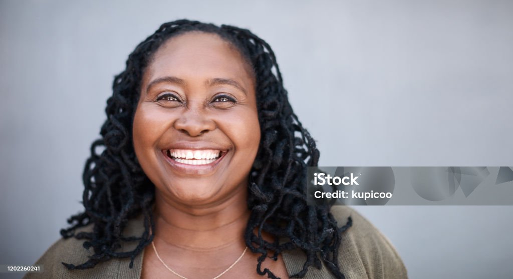 Everything in my life has fallen into place Portrait of a mature woman standing against a grey background Women Stock Photo