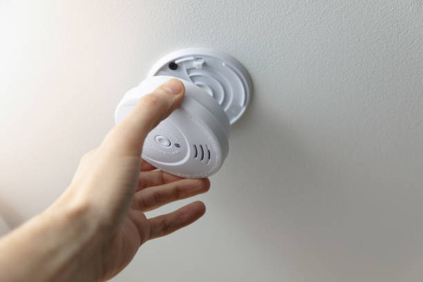 istock hand installing smoke detector on the room ceiling 1202260403