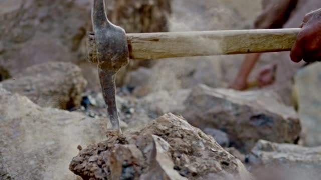 Miner or gold digger breaking rock by digging axe . Close up of pickaxe hitting rocks .  Shot on RED EPIC DRAGON Cinema Camera in slow motion.