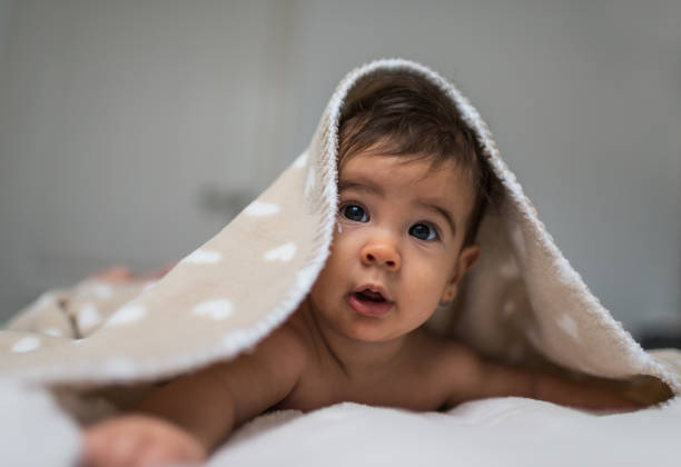 istock Cute baby girl in bed under a fluffy blanket 1202261002
