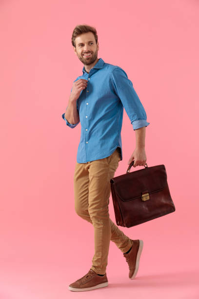 istock happy casual man holding suitcase and fixing shirt 1202261130