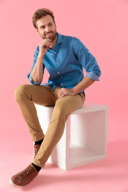 istock happy casual man holding elbow on knee and smiling 1202262949