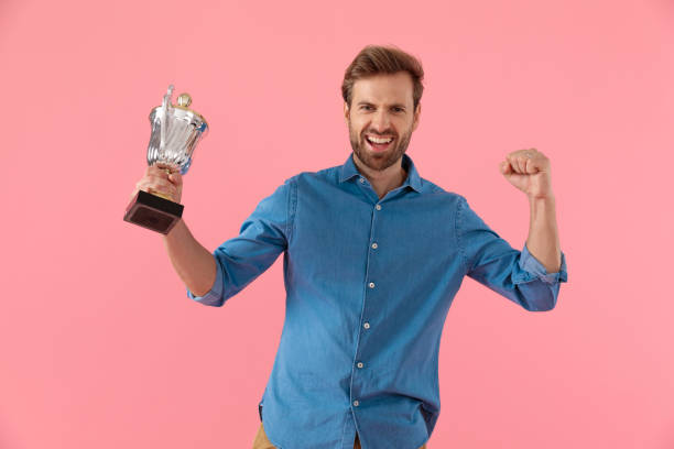 istock excited casual guy holding trophy and celebrating victory 1202263231