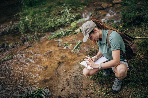 One female biologist taking water sample for research in nature