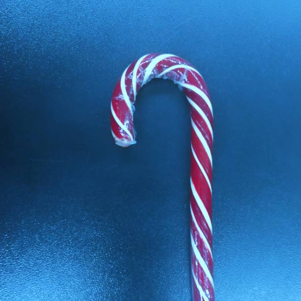 istock Red and white candy cane on classic blue metal background. 1202263740