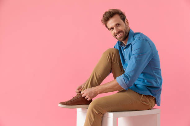 happy young casual man arranging trousers and smiling