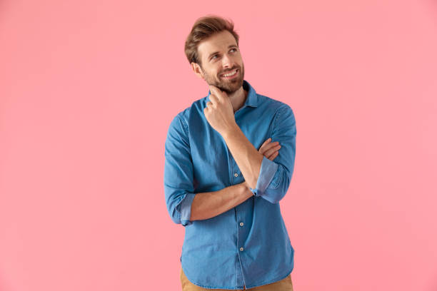 happy casual guy in denim shirt smiling and dreaming happy casual guy in denim shirt smiling and looking up, dreaming, standing on pink background man thinking stock pictures, royalty-free photos & images