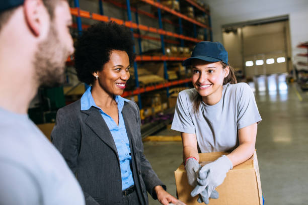istock Young manual workers with inspector at warehouse packing boxes 1202267759