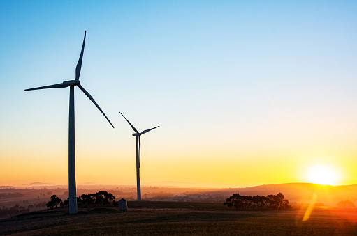 Wind turbine silhouettes with the sun rising over the horizon