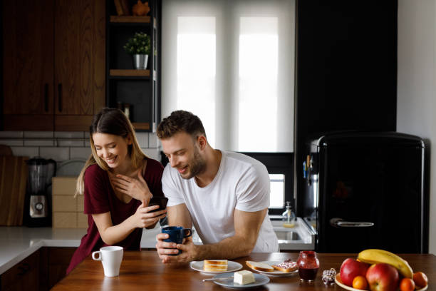istock Happy young couple using smart phone together during breakfast at home 1202268061