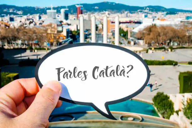 closeup of the hand of a caucasian man showing a speech bubble with the question parles catala?, do you speak Catalan written in Catalan, at Montjuic Hill, in Barcelona, Spain