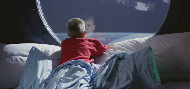 istock Boy looking out of spaceship window 1202269223