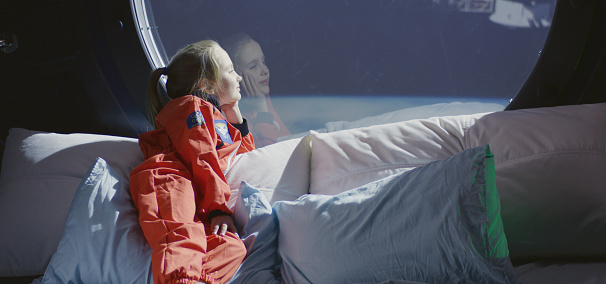 Medium shot of a girl enjoying view from a spaceship