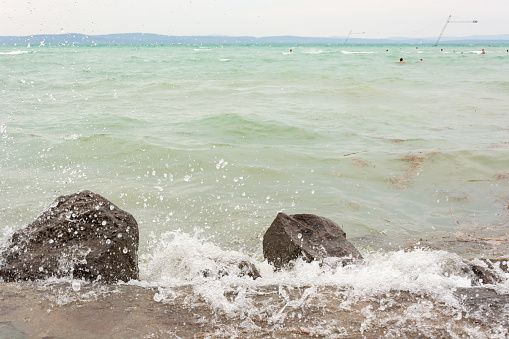 Big stones on the shores of Lake Balaton in rainy weather in summer 2019.The photo shows waves crashing against stones. Picture taken in Siofok town - the most popular holiday destination in Hungary.