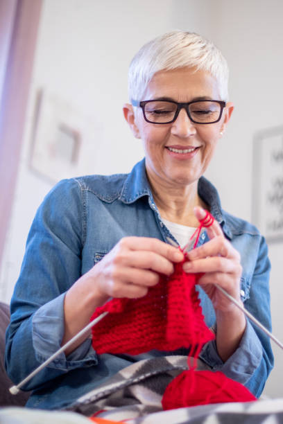 istock Mature woman sitting on a sofa and knitting. 1202271371