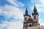 View of the sharp towers of the Church of Mother of God before Týn against vibrant blue sky and white couds. Prague, Chezh Republic