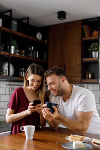 istock Happy young couple using smart phone together during breakfast at home 1202272939