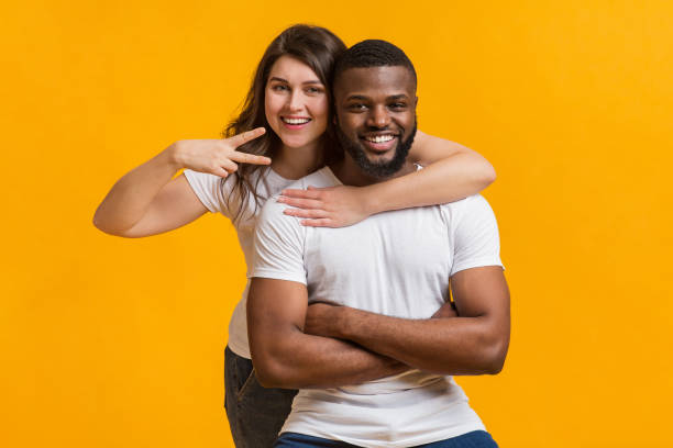 istock Millennial couple embracing and posing together on yellow background 1202273099