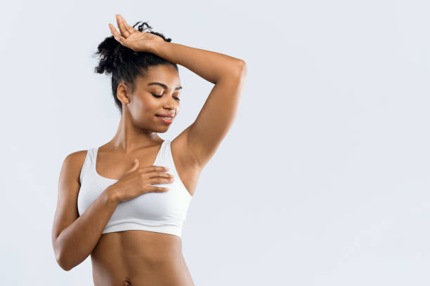 istock Happy black woman smelling her armpit over grey background 1202273140