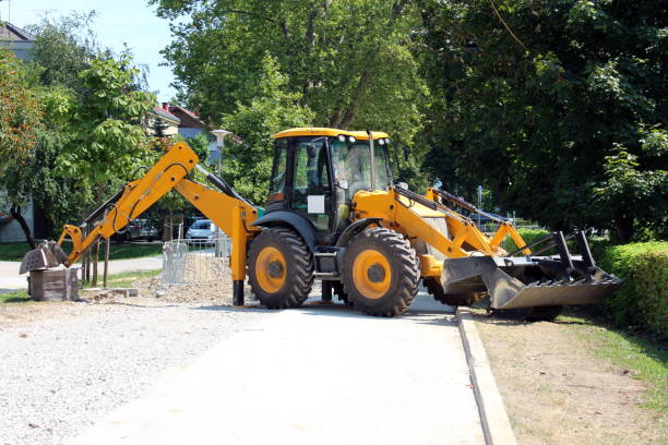 istock Large industrial backhoe loader parked across local road to prevent access to construction site surrounded with dense trees 1202273722