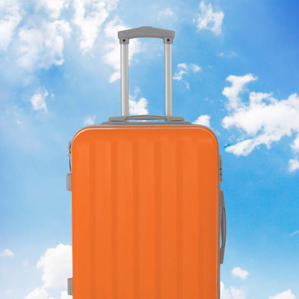 istock Orange luggage close-up, sky background 1202274122