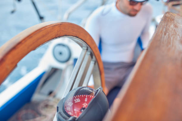 istock Sailor using wheel to steer rudder on a sailing boat. 1202277165