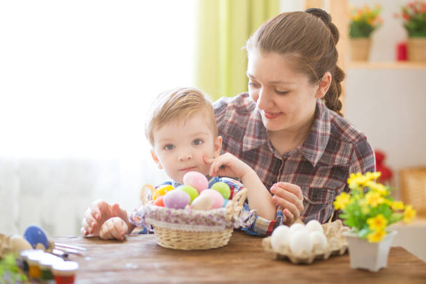 istock Happy time while painting easter eggs. Easter concept. Happy mother and her cute child getting ready for Easter by painting the eggs 1202277362