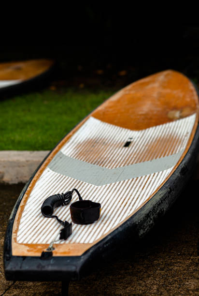 istock SUP / Stand up Paddle Board Get ready . Surfboard and paddle with Ankle Leash Rope Coiled Stand Up Paddle Board Surfing Cord String on a river lake water . Water sport, happy active summer vacation 1202279426