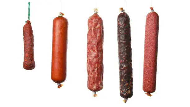 Photo of Different hanging sausages isolated on white background