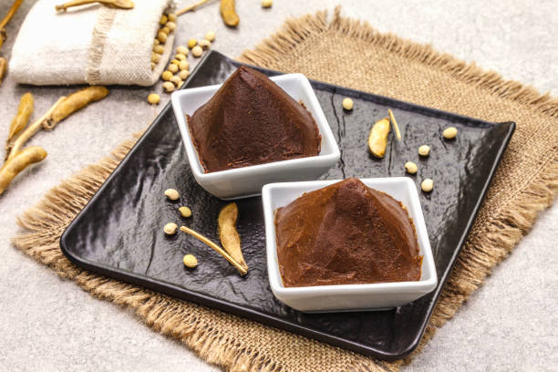 Miso paste, traditional Japanese seasoning. Two types, dark and light brown with dry soya beans. Sackcloth, bag, pods. Stone concrete background