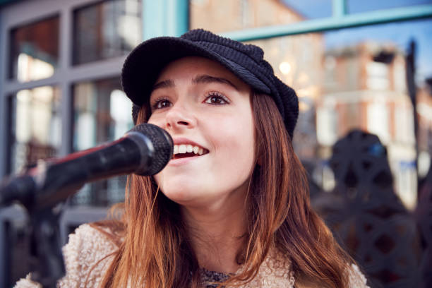 musikerin busking singing outdoors in street - street musician stock-fotos und bilder