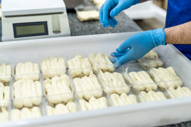istock Confector's hands with desserts in plastic package putting it for freezing. Industrial manufacturing of food 1202285528