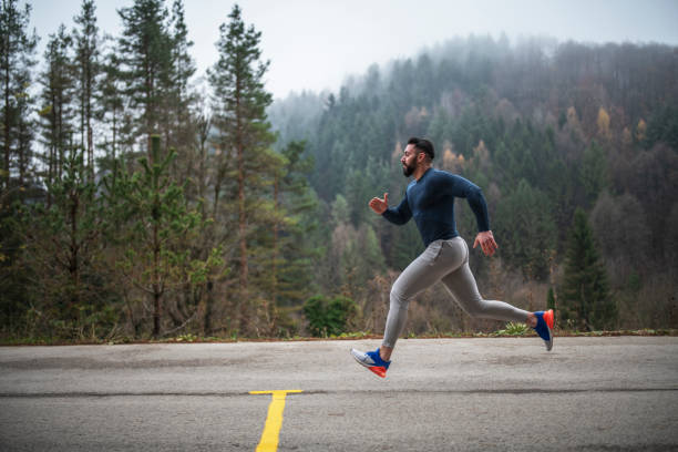 sportif courant sur la route en automne. - distance running jogging running fog photos et images de collection