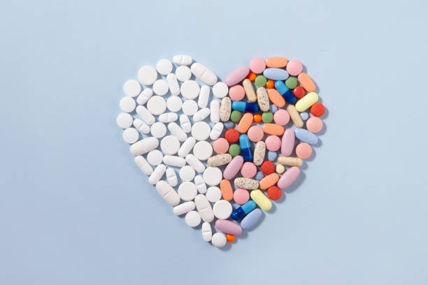 istock Heart Shaped White and Colored Pills on Blue Background 1202286818