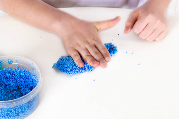 istock Kids hands make crafts from blue balls plasticine, playfoam, shiny clay. Process sculpt figures in play for education concept. 1202287069