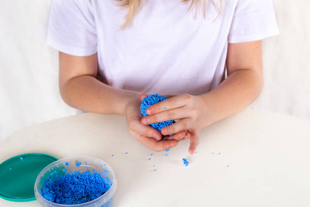 istock Kids hands make crafts from blue balls plasticine, playfoam, shiny clay. Process sculpt figures in play for education concept. 1202287070