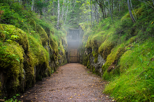 Entrance drift or shaft to an old abandoned and closed down mine in Sweden. Mist is forming above the gate from the cold air rising from the shaft