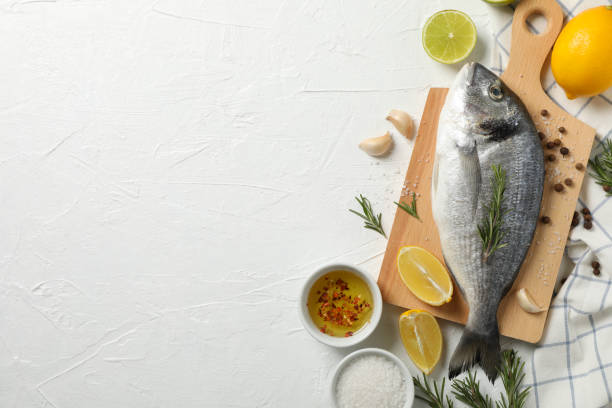 istock Cutting board with Dorado fish and cooking ingredients on white background, space for text 1202288325