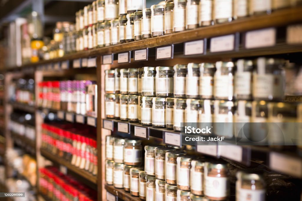 Spices in glass jars at store Large assortment of natural seasonings and spices in glass jars on store counter Spice Stock Photo
