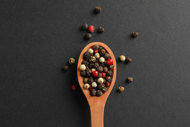 istock Wooden spoon with pepper spice on black background, top view 1202292147