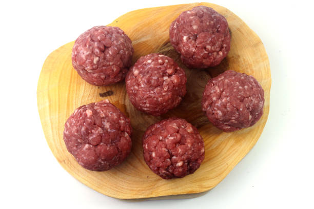 istock closeup fresh raw meatballs beef isolated over white background on rustic wooden board 1202292760