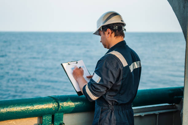 istock Deck Officer on deck of offshore vessel or ship , wearing PPE personal protective equipment. He fills checklist. Paperwork at sea 1202294796