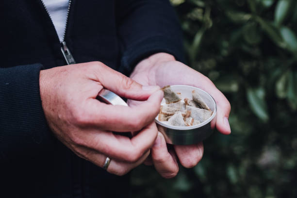 istock Hands picking up a portion of snuff, snus nicotin pad from the box 1202294968