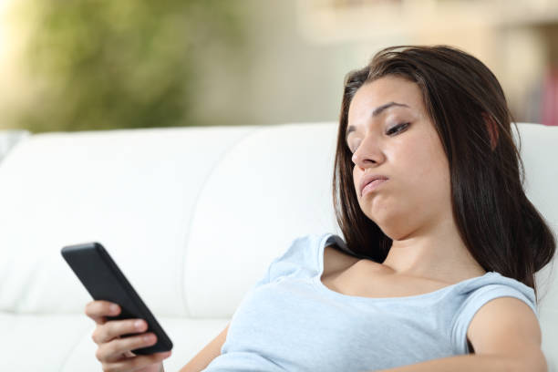 Bored girl checking mobile phone at home Bored girl checking mobile phone at home wasting time photos stock pictures, royalty-free photos & images