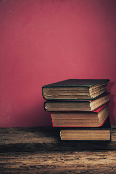 istock Beautiful old books on a oak wooden table. RED wall background. 1202298607