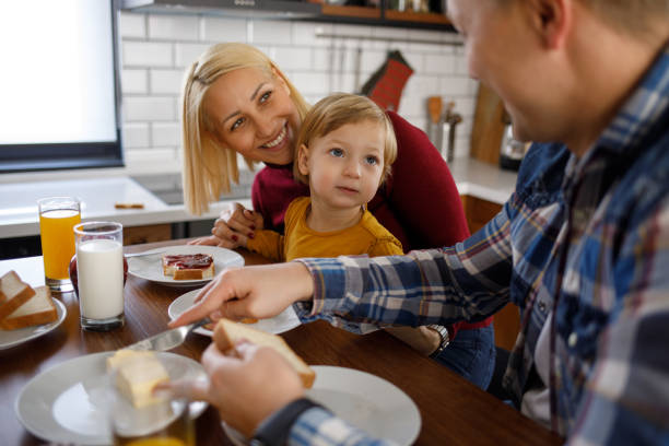 istock Young happy family having breakfast at home 1202298702
