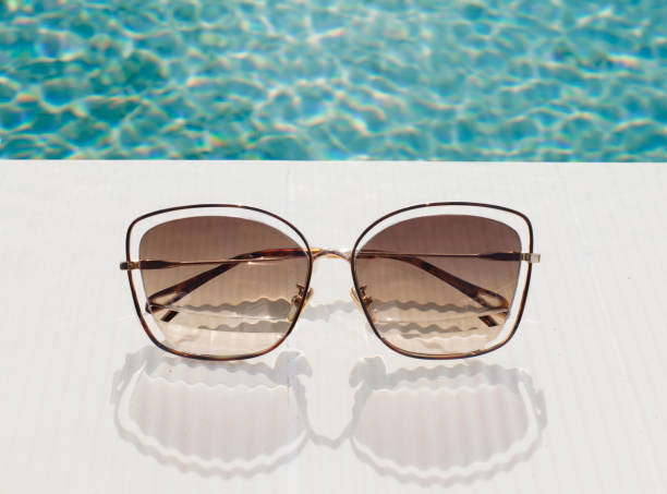istock Design sunglasses on swimming pool edge 1202299787